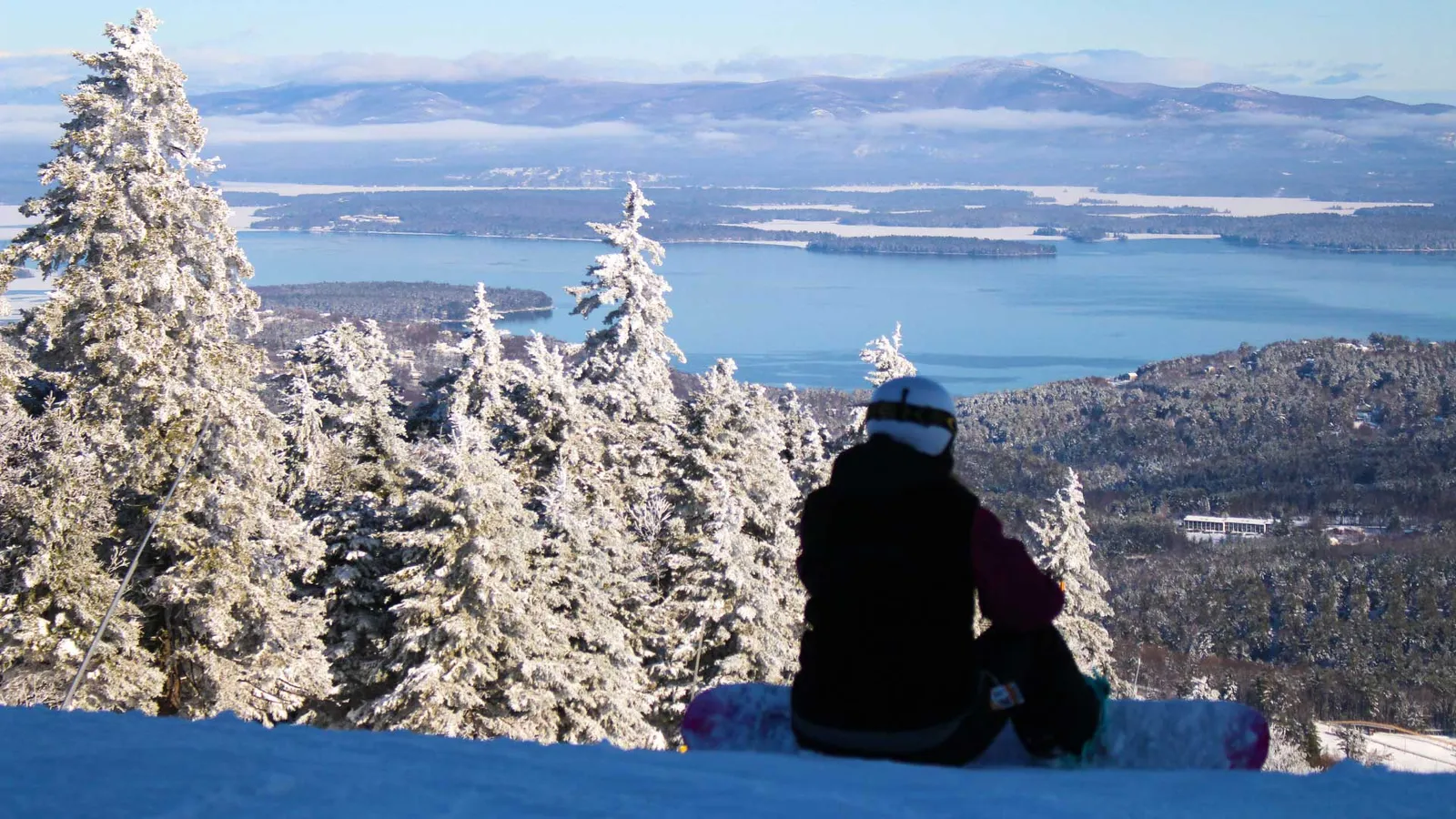 Snowboarder overlooking Lake Winnipesaukee from Gunstock Mountain Resort in winter