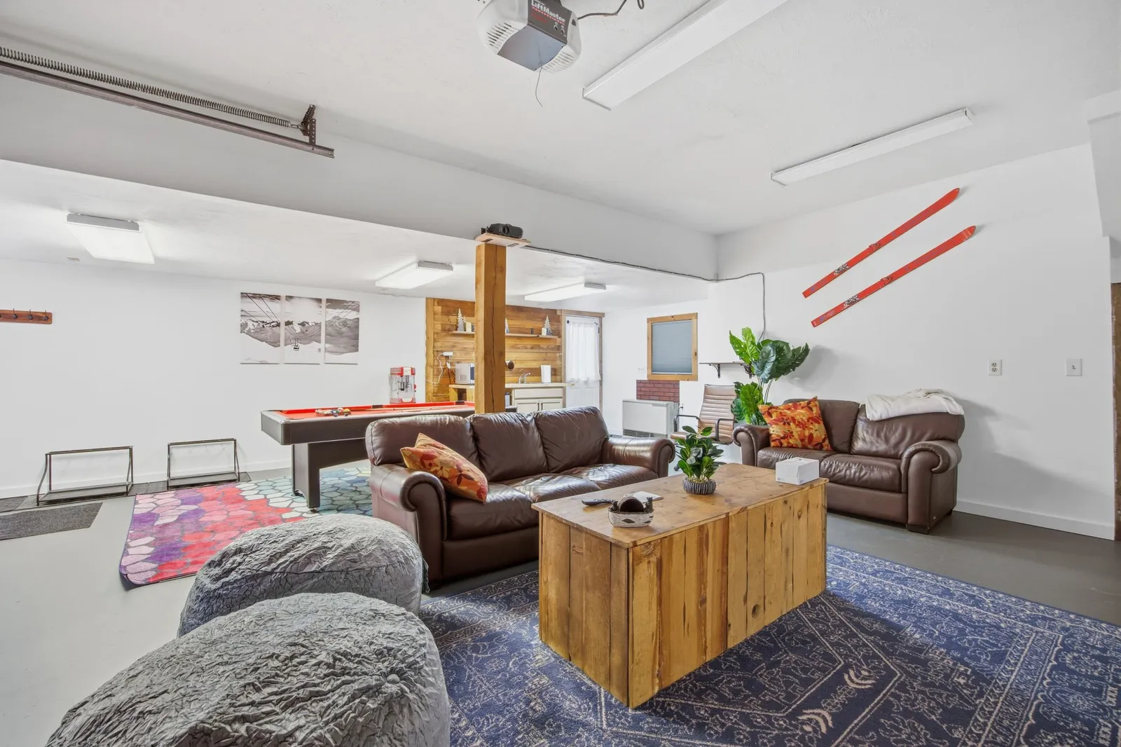 Lower-level game room with a pool table, leather couches, and ski decor on the walls